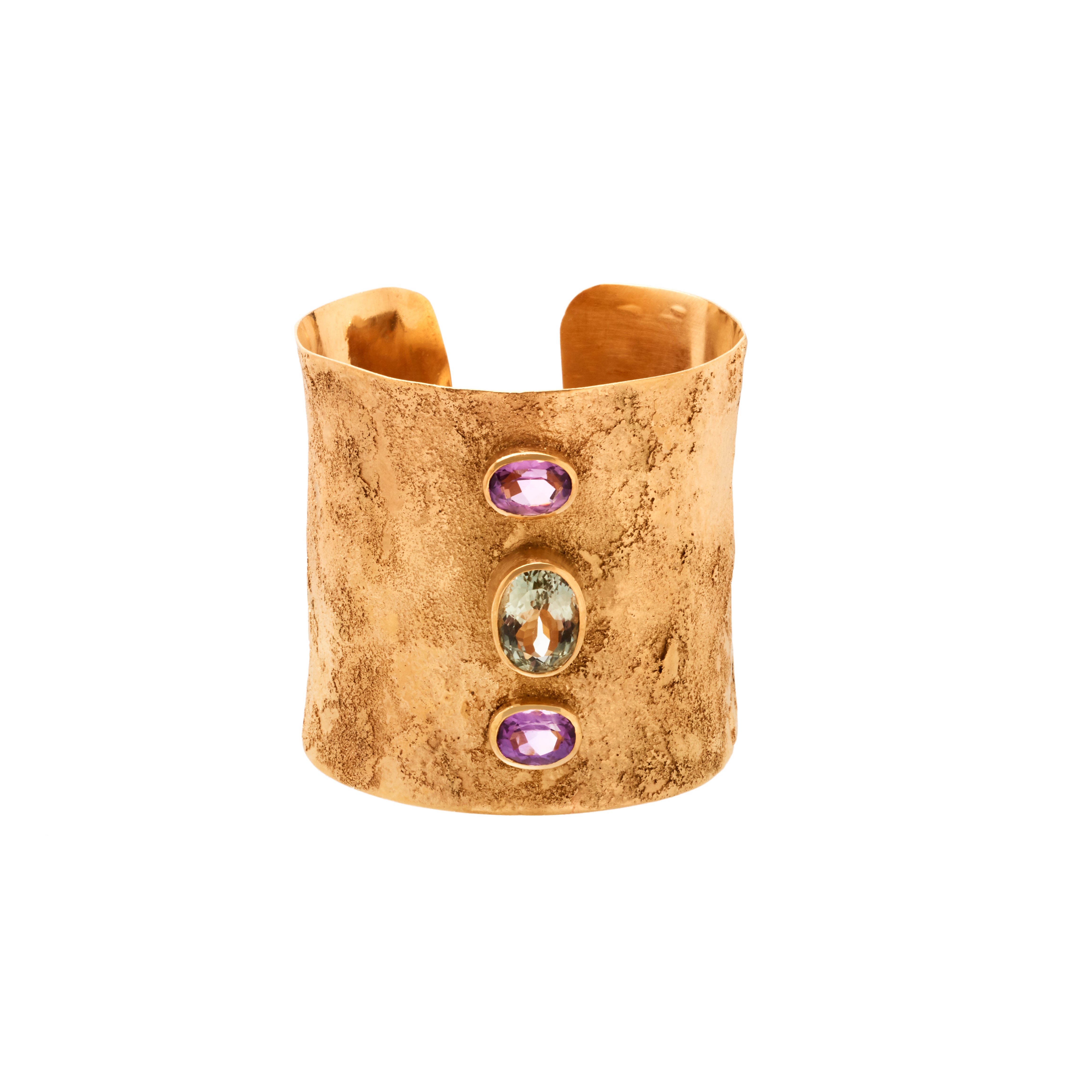 Gold cuff bracelet with three gemstones on a white background